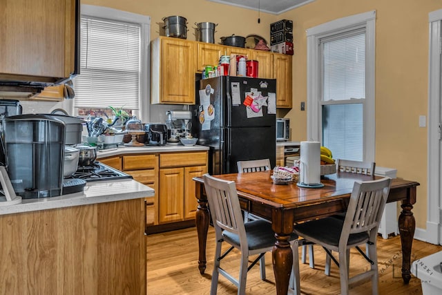 kitchen with light wood-style flooring, light countertops, and freestanding refrigerator