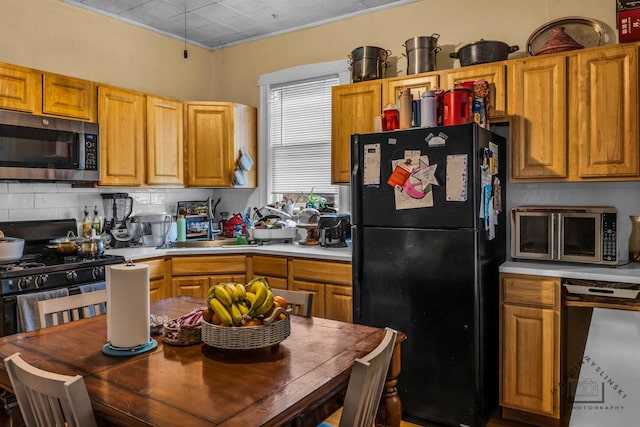 kitchen with brown cabinetry, appliances with stainless steel finishes, light countertops, and decorative backsplash