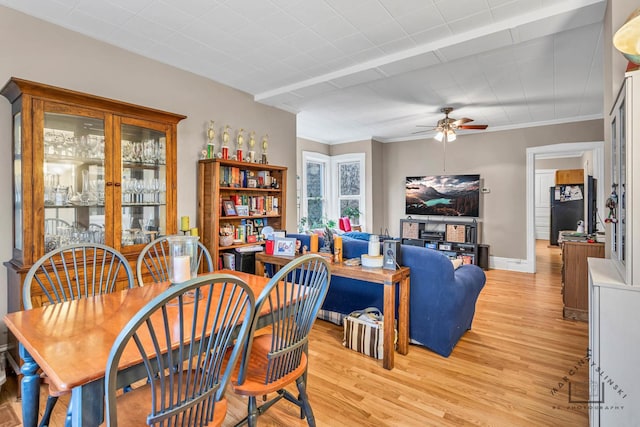 dining space with light wood-style floors, crown molding, baseboards, and ceiling fan