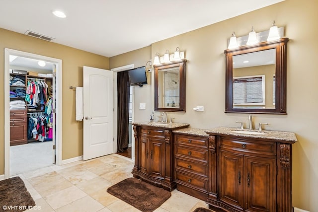 bathroom featuring double vanity, a spacious closet, visible vents, and a sink