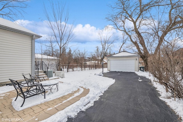 yard layered in snow with an outdoor structure and a detached garage