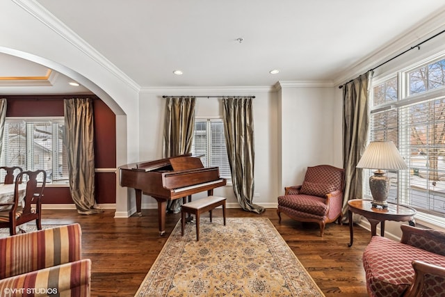 sitting room with dark wood-style floors, arched walkways, crown molding, and baseboards