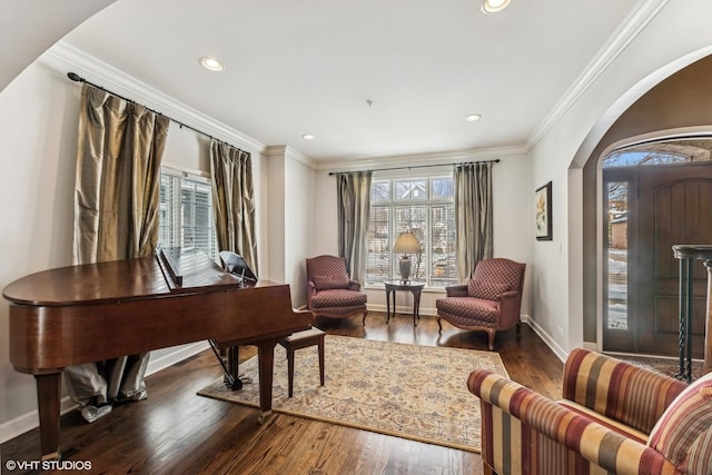 sitting room featuring arched walkways, ornamental molding, dark wood-style floors, and baseboards