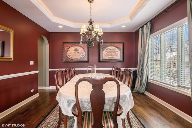 dining area with a tray ceiling, a healthy amount of sunlight, arched walkways, and baseboards