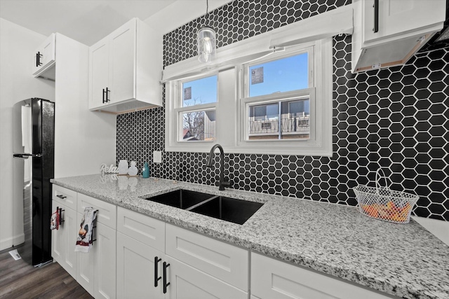 kitchen featuring white cabinets, decorative light fixtures, decorative backsplash, sink, and black fridge