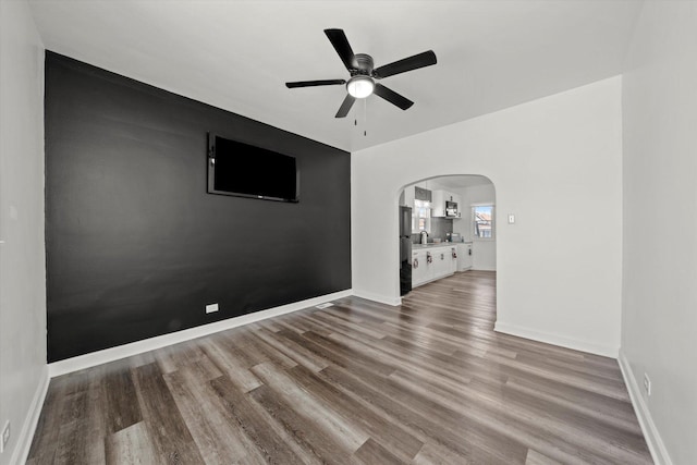 unfurnished room with sink, ceiling fan, and wood-type flooring