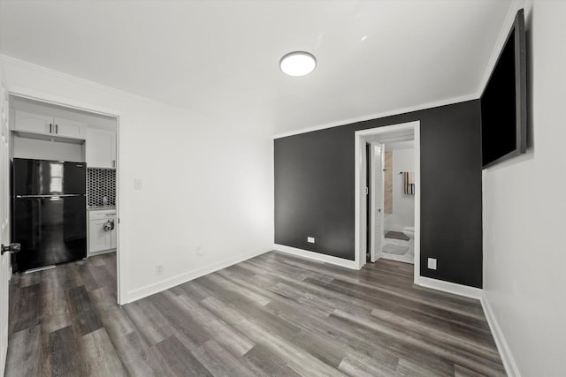 empty room featuring dark wood-type flooring and crown molding