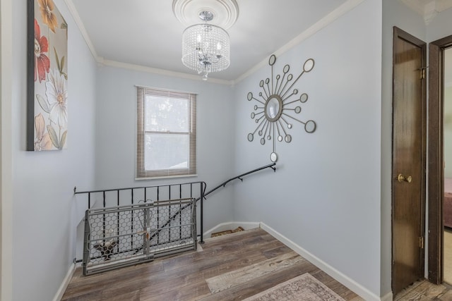 stairway featuring an inviting chandelier, baseboards, crown molding, and wood finished floors