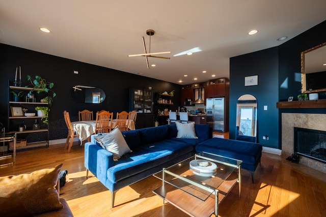 living area with arched walkways, a fireplace, wood finished floors, and recessed lighting