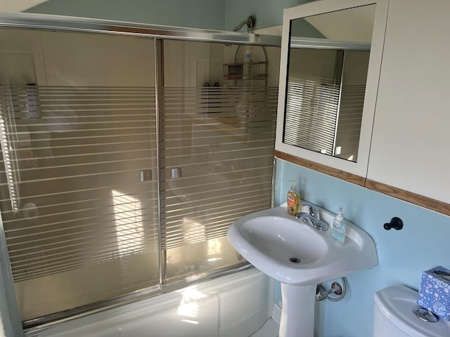 bathroom featuring combined bath / shower with glass door and toilet