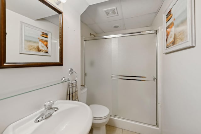 bathroom with a drop ceiling, sink, a shower with shower door, and toilet