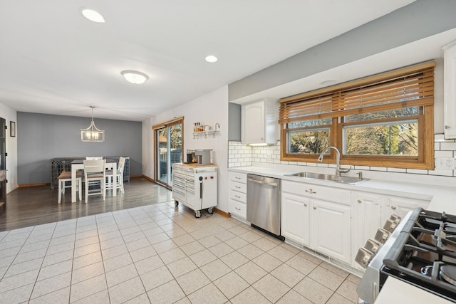 kitchen with white cabinetry, stainless steel appliances, sink, backsplash, and pendant lighting