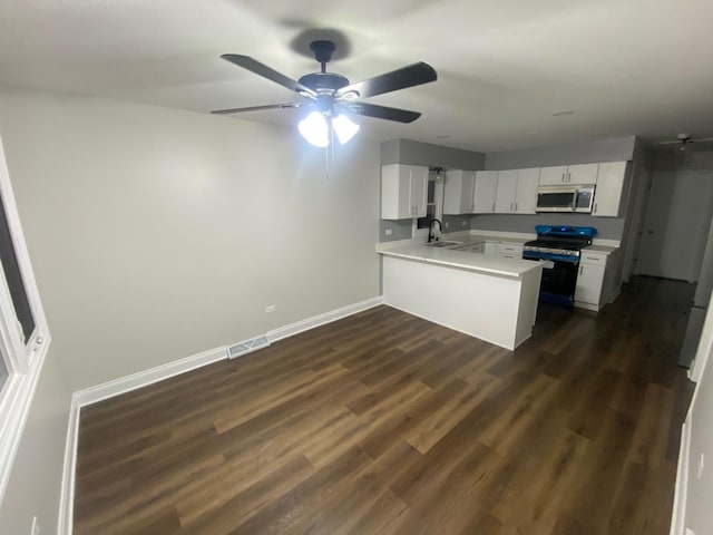 kitchen with white cabinetry, kitchen peninsula, dark hardwood / wood-style flooring, sink, and appliances with stainless steel finishes