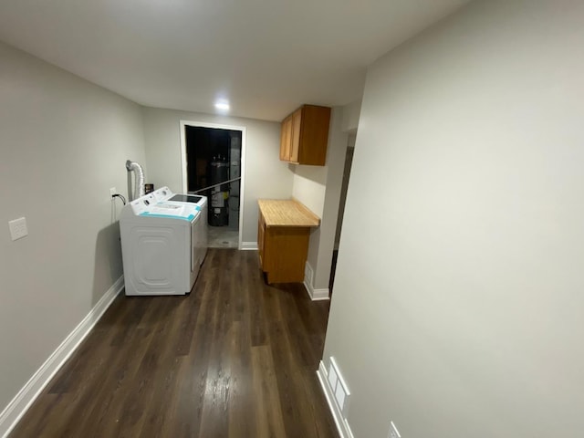 clothes washing area with cabinets, water heater, washer and clothes dryer, and dark hardwood / wood-style floors