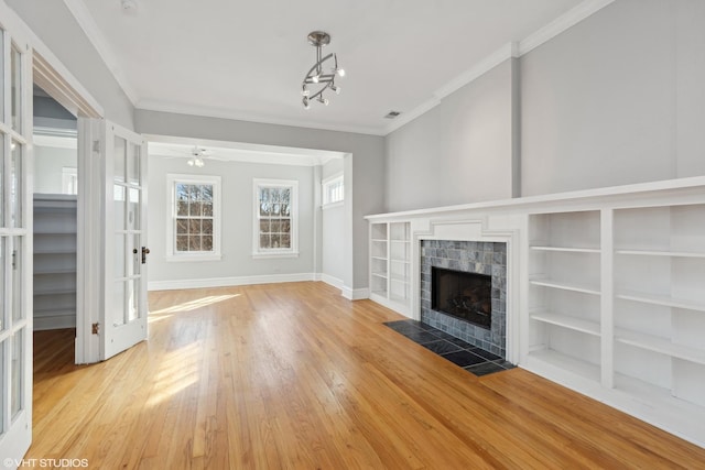 unfurnished living room with ornamental molding, a tiled fireplace, and light hardwood / wood-style flooring