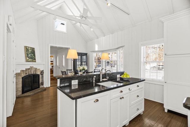 kitchen with dark hardwood / wood-style floors, ceiling fan, sink, white cabinetry, and a kitchen island with sink