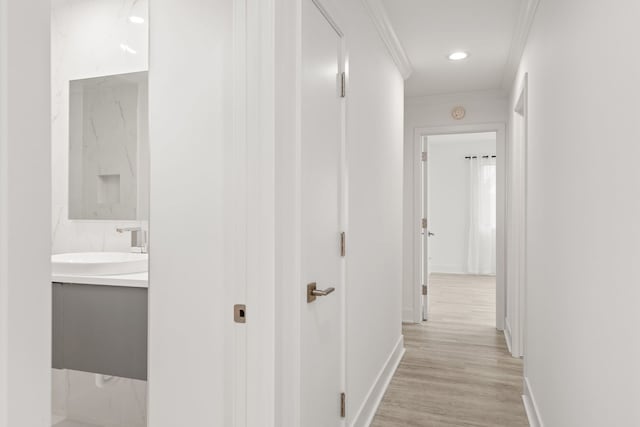 corridor featuring light hardwood / wood-style flooring, sink, and crown molding