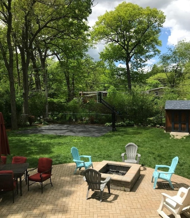 view of patio with an outdoor structure, a fire pit, and a storage unit