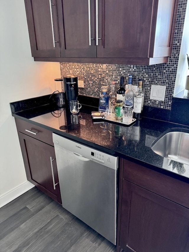 interior space featuring dark wood-style floors, backsplash, stainless steel dishwasher, dark brown cabinets, and dark stone counters