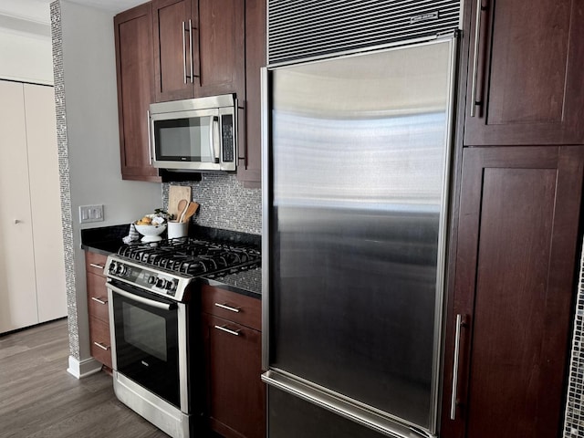 kitchen with dark brown cabinets, appliances with stainless steel finishes, dark wood finished floors, and decorative backsplash