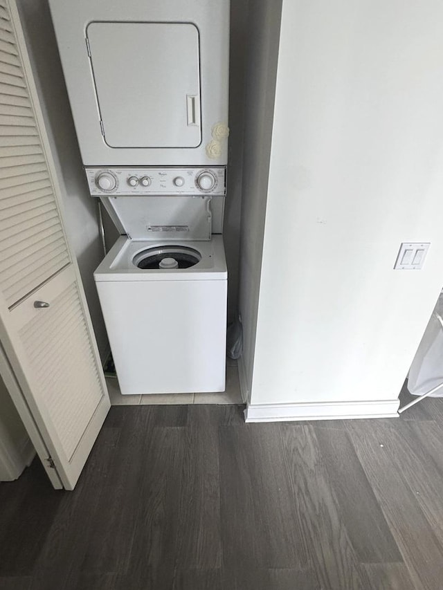 laundry room with laundry area, dark wood-type flooring, and stacked washer / drying machine