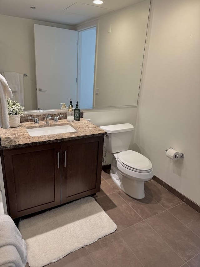 bathroom featuring toilet, tile patterned floors, baseboards, and vanity