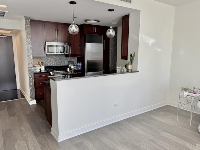 kitchen with wood finished floors, visible vents, appliances with stainless steel finishes, tasteful backsplash, and dark countertops