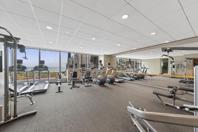 gym with a wall of windows, a paneled ceiling, and recessed lighting