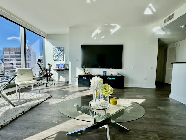 living room featuring baseboards, floor to ceiling windows, visible vents, and wood finished floors