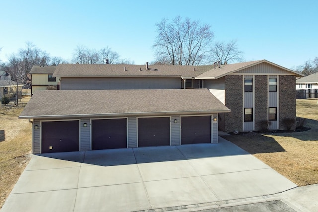 view of front facade with a shingled roof, driveway, and a garage