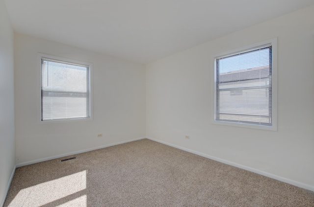 unfurnished room featuring carpet floors, a healthy amount of sunlight, visible vents, and baseboards