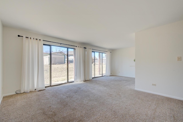 carpeted spare room featuring baseboards