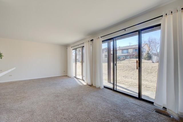 unfurnished room featuring carpet flooring, visible vents, and baseboards