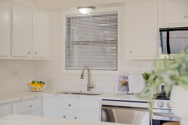 kitchen featuring decorative backsplash, white cabinets, a sink, and dishwashing machine