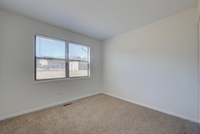 empty room featuring carpet, visible vents, and baseboards