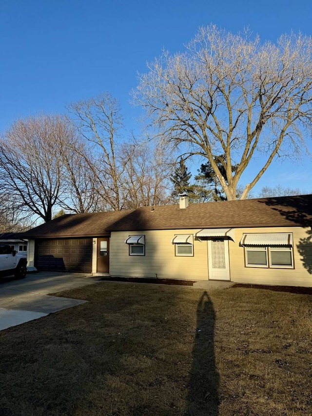 ranch-style home featuring driveway, a front lawn, a chimney, and an attached garage