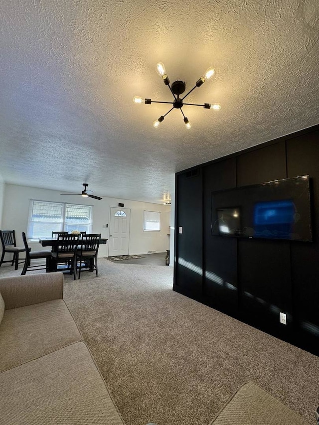 living area featuring a ceiling fan, carpet flooring, and a textured ceiling