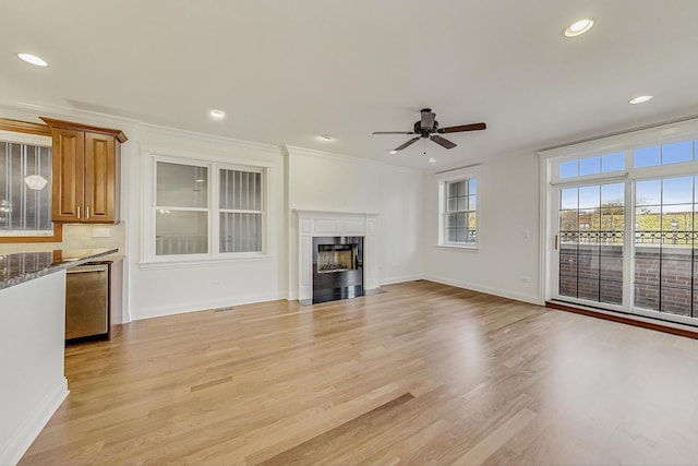 unfurnished living room featuring recessed lighting, a fireplace with flush hearth, baseboards, ornamental molding, and light wood-type flooring