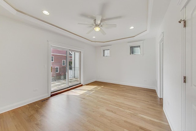 spare room featuring a tray ceiling, baseboards, ceiling fan, and light wood finished floors