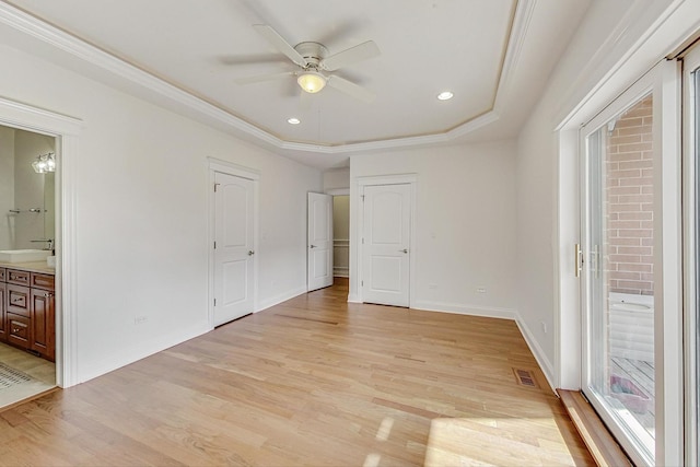 unfurnished bedroom with visible vents, a raised ceiling, baseboards, ensuite bath, and light wood-type flooring