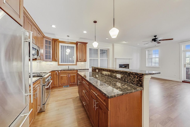 kitchen featuring a center island, light wood finished floors, stainless steel appliances, decorative backsplash, and brown cabinetry