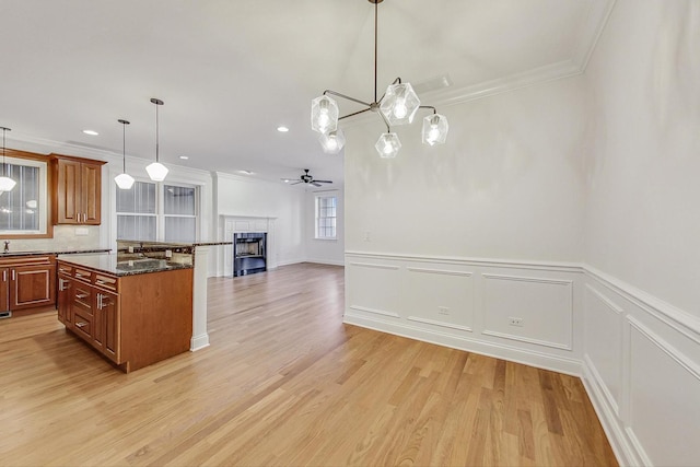 kitchen with open floor plan, brown cabinetry, and crown molding