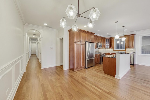 kitchen with appliances with stainless steel finishes, brown cabinetry, and ornamental molding