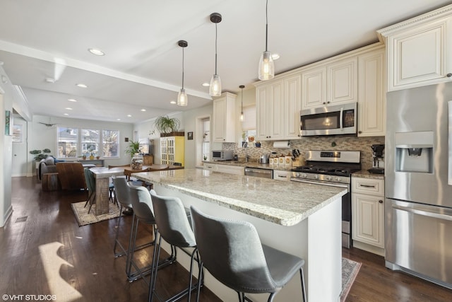 kitchen featuring light stone counters, decorative light fixtures, decorative backsplash, appliances with stainless steel finishes, and open floor plan