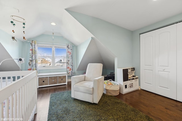 bedroom featuring a closet, vaulted ceiling, dark wood finished floors, and a crib