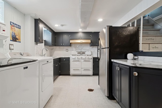 kitchen featuring washer and clothes dryer, range with two ovens, light countertops, under cabinet range hood, and a sink