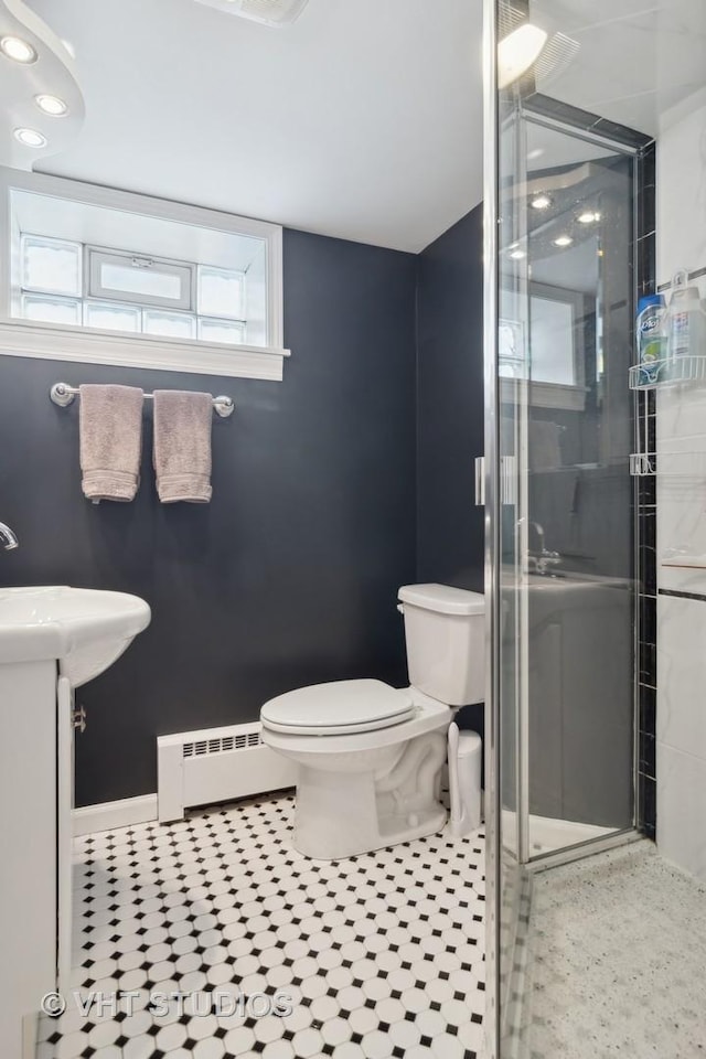 full bath with toilet, vanity, baseboard heating, a shower stall, and tile patterned floors