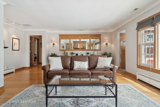 living room with ornamental molding, baseboard heating, and wood finished floors