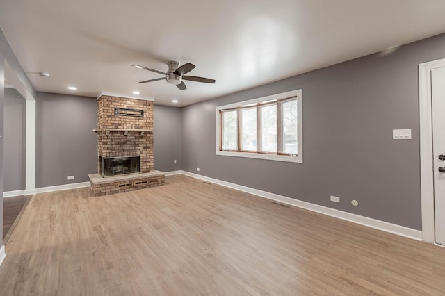 unfurnished living room with baseboards, ceiling fan, wood finished floors, a fireplace, and recessed lighting