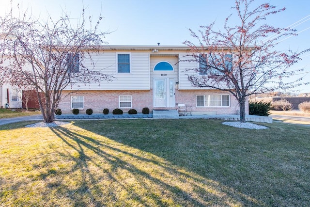 split foyer home featuring brick siding and a front yard